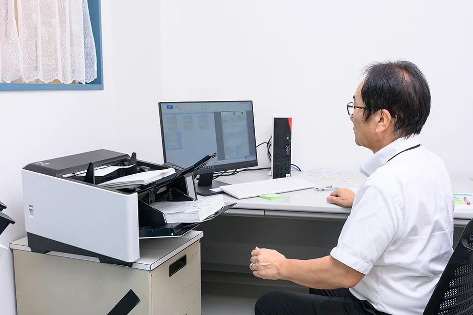 fi-8950の前に座る宮下さんの写真