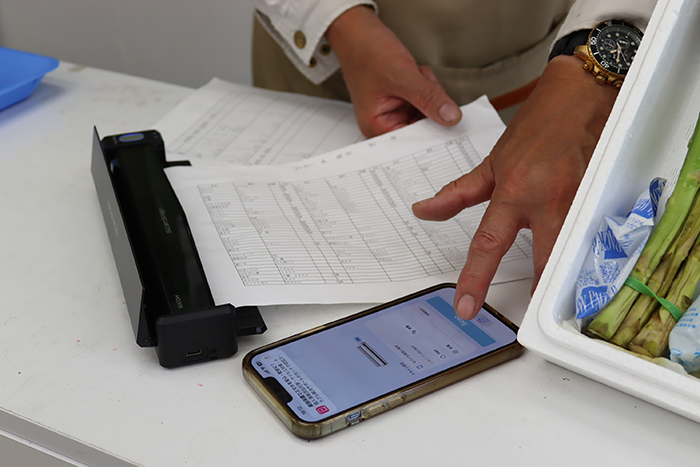 スマホから操作し、ScanSnap iX110で書類をスキャンする様子。